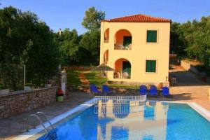 a house with a swimming pool in front of a house at Emily's Apartments in Kassiopi