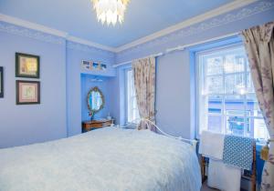 Dormitorio azul con cama y ventana en Candlemaker Old Town 500m from Edinburgh Castle en Edimburgo