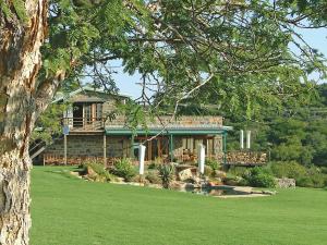 una casa con porche y patio verde en Spion Kop Lodge, en Winterton