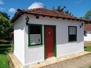 ein kleines Haus mit einer roten Tür und Fenstern in der Unterkunft Pouso Jequitibá in Tiradentes