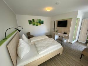 a bedroom with a white bed and a television at Motel Espenhof in Ladbergen
