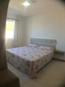 a bedroom with a bed with a floral bedspread at Apartamento na Praia de Palmas Gov. Celso Ramos in Governador Celso Ramos