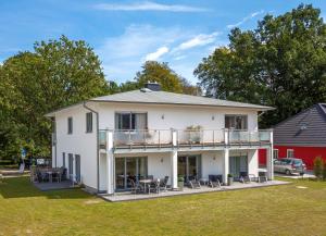 a white house with a balcony and tables and chairs at Villa Kaja Wohnung Ostseestrand in Korswandt