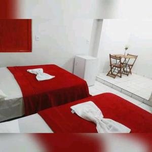 Mundial Hotel في غويانيا: غرفة نوم بسريرين مع شراشف حمراء وطاولة