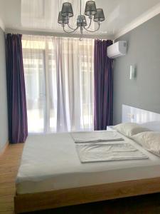ラザレフスコエにあるГостевой дом Мелия familyのベッドルーム1室(紫色のカーテンが付いた大型ベッド1台付)