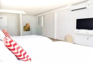 a white bedroom with a bed and a flat screen tv at Villas Marlin 108, a pie de playa, albercas, jacuzi, ubicacion inmejorable in Cancún