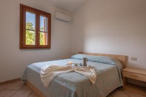 een slaapkamer met een bed, een wastafel en een raam bij Le Dimore di Budoni in Budoni