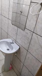 a bathroom with a white sink and tiled walls at Hotel Gringos in Londrina