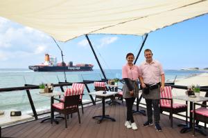 a man and woman standing on a deck with a ship in the background at Hotel Truida in Vlissingen
