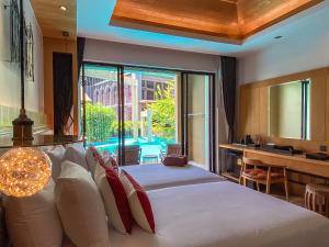 カタビーチにあるAurico Kata Resort & Spa - SHA Extra Plusのベッドルーム1室(大きなベッド1台、大きな窓付)