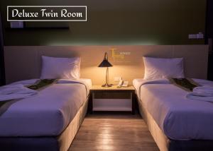 a hotel room with two beds and a table with a lamp at Thongmanee Hotel in Hat Yai