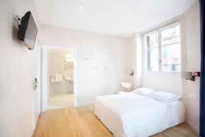 a white bedroom with a white bed and a window at Nadaud Hotel in Paris