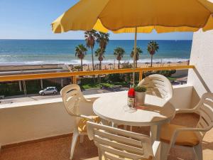 a table with chairs and an umbrella on a balcony with the beach at T1 Praiamar 3 Vista Fabulosa in Quarteira