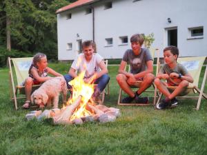 a group of kids sitting around a fire with a dog at Agroturystyka w Lesie in Dzierzążno