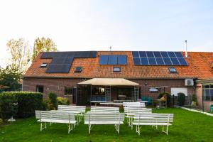 un groupe de bancs blancs devant un bâtiment doté de panneaux solaires dans l'établissement Kwakkelnest, à Poperinge