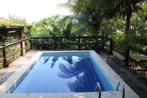 een blauw zwembad met een hek en bomen bij Pousada Afrika in Búzios