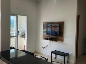 een woonkamer met een tafel en een tv aan de muur bij AP 71 COSTA VERDE PRAIA GRANDE in Praia Grande