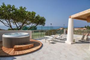 un patio con bañera de hidromasaje y tumbonas en Baia Del Sole Resort, en Capo Vaticano