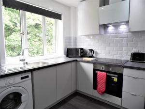 una cocina con fregadero y lavadora en Penilee Upper Apartment, en Glasgow