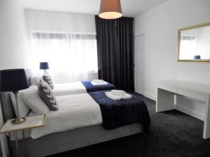 a bedroom with a bed with a desk and a window at Penilee Upper Apartment in Glasgow