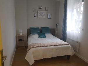 una camera da letto con un letto con cuscini blu e una finestra di F3 l'escale Conviviale - Villepinte Aéroport CDG - Parc Astérix - Paris a Mitry-Mory