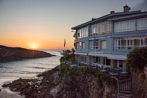 a building on a cliff next to the ocean at Hotel Sablón in Llanes