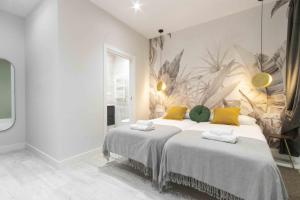 1 dormitorio blanco con 2 camas y almohadas amarillas en The Rentals Collection - Getaria, en San Sebastián