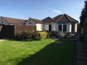 a house with a yard with chairs and a fence at Redcot holiday bungalow in Peover Superior