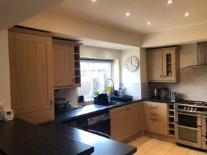 a kitchen with wooden cabinets and a clock on the wall at Redcot holiday bungalow in Peover Superior