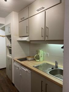 eine Küche mit weißen Schränken und einem Waschbecken in der Unterkunft Appartement Les Menuires in Les Menuires