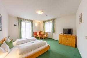 um quarto com 2 camas, uma televisão e uma mesa em Hotel Garni Angerer em Lutago