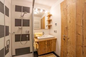 ein Bad mit einem Waschbecken und einer Dusche in der Unterkunft Hotel Garni Angerer in Luttach