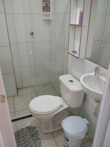 a white bathroom with a toilet and a sink at Paraíso da Deise in Mata de Sao Joao