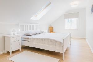 a white bedroom with a white bed and a window at Wiigi Apartments in Haapsalu