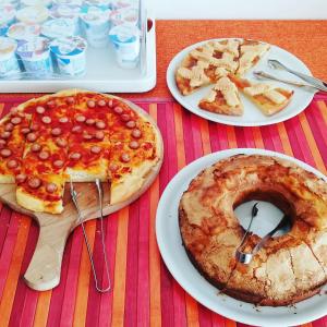 una mesa con dos platos de pizza y un pastel en Hotel Villa Elia en Rímini