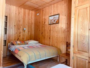 een slaapkamer met een bed in een houten hut bij Cunami in Nida