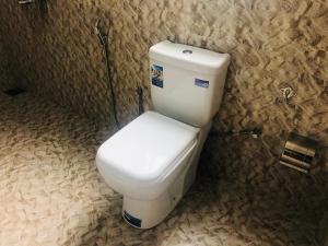 een badkamer met een wit toilet in een stenen muur bij Boo Kirinda Holiday Resort in Badulla