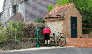 una persona está de pie junto a una bicicleta en la acera en The Blue Bell, en Midhurst