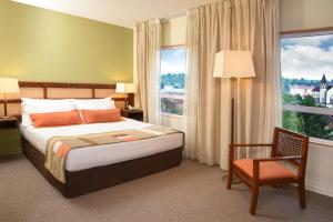 a bedroom with a bed and a chair and a window at Solace Hotel Puerto Varas in Puerto Varas