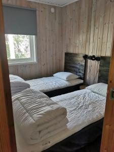 two beds in a room with wooden walls at Fjällstuga i Foskros m bastu in Idre