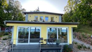 a small yellow house with a deck and windows at Dünenhaus Seensucht in Thiessow