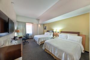 um quarto de hotel com duas camas e uma televisão de ecrã plano em Holiday Inn Guadalajara Select, an IHG Hotel em Guadalajara