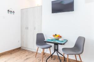 einen Tisch mit drei Stühlen und eine Schale Obst darauf in der Unterkunft Bossa nova Apartment in Herceg-Novi