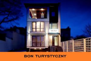 a tall white building at night with the words bon tuminyomy at Villa Gardena in Gdynia