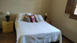 a bedroom with a white bed with pillows on it at Casita de Piedra in Trinidad