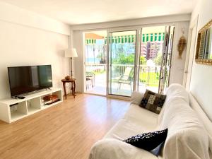 un salon avec un canapé blanc et une télévision dans l'établissement Apartamento de moderno en Salou, à Salou
