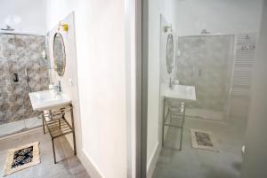 ein Badezimmer mit zwei Waschbecken, einer Dusche und zwei Spiegeln in der Unterkunft Piombino 1428 in Piombino