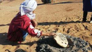 a woman is playing in the sand in the desert at Maison d'hôtes Dar Farhana in Ouarzazate