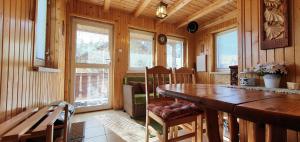a dining room with a wooden table and some windows at Chalúpka u Babičky in Ždiar