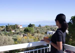 a woman standing on a balcony holding a drink at Principe Alogna Hotel & SPA in Altavilla Milicia